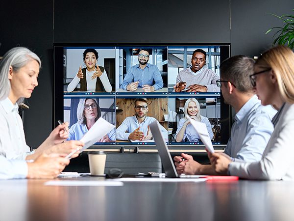 Bild eines Büro-Konferenztisches mit Mitarbeitern und einem interaktiven Display